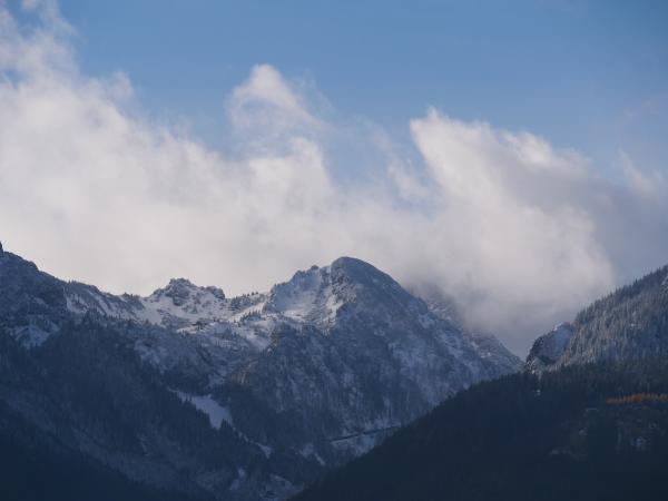 Rugged mountain terrain covered in snow with clouds settled around the peaks.