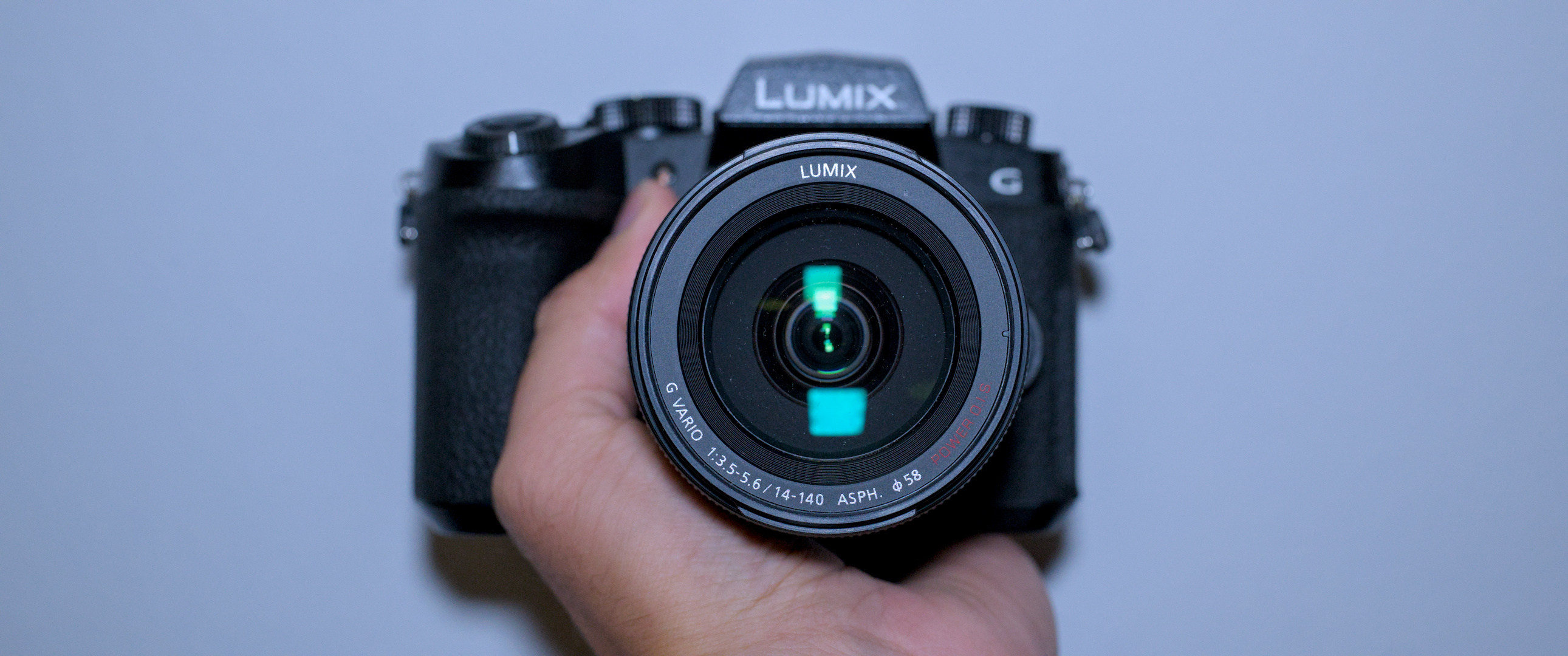 A photo of my hand holding a camera with the lens looking into the lens of the camera taking the photo.
