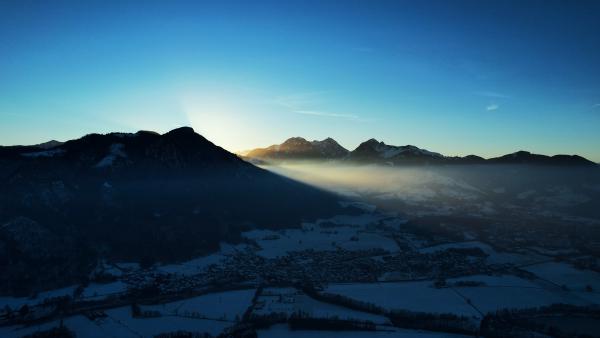 Sunrise illuminating the peaks of the Alps with a clear blue sky.