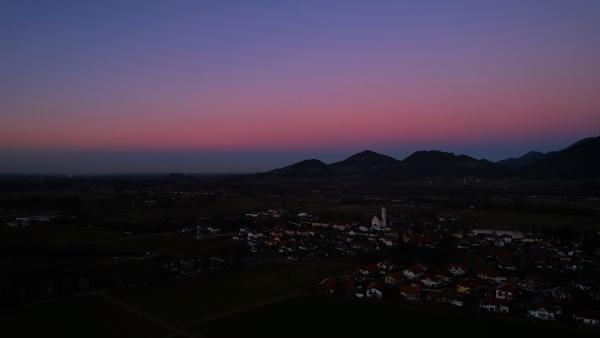 Twilight over a quaint Bavarian village with a backdrop of mountains.