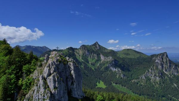 Rugged Bavarian mountain landscape with a cross on top of rocky peaks.