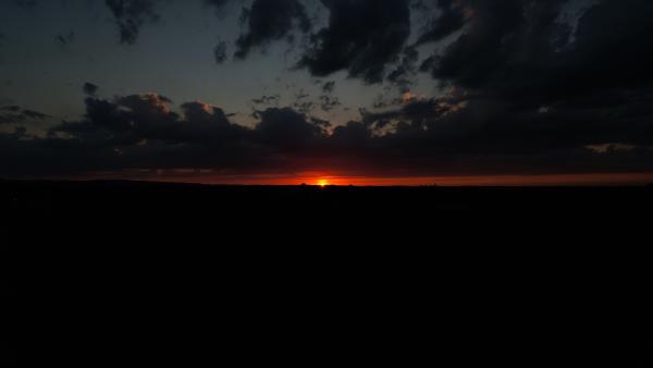 The sunset creating a fiery skyline with dark cloud silhouettes.