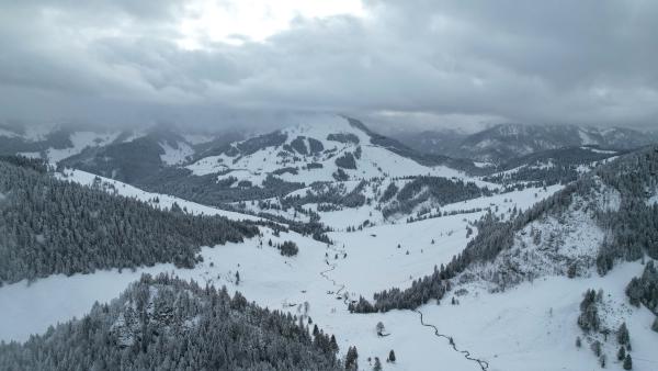 Photo of a little valley between the mountains. The image was taken in winter and everything is snow covered.