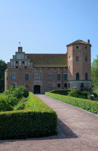 A swedish castle with the way towards it. You can see the green of the castles garden on the right and left to the way.