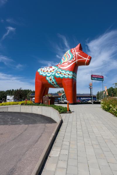 The largest dalar horse of the world standing next to a parking lot.