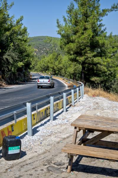 A car resting area next to a road threw a turkish forest.