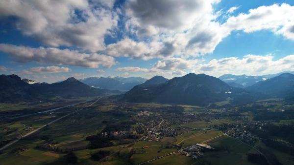Expansive view of grasslands leading up to majestic mountains under a cloudy sky.
