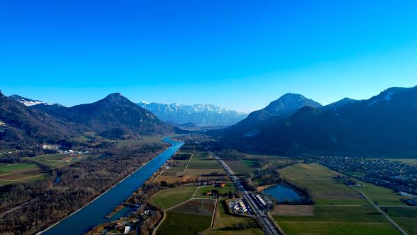 A vibrant aerial view of the Inn Valley with the river snaking through and mountains in the distance.