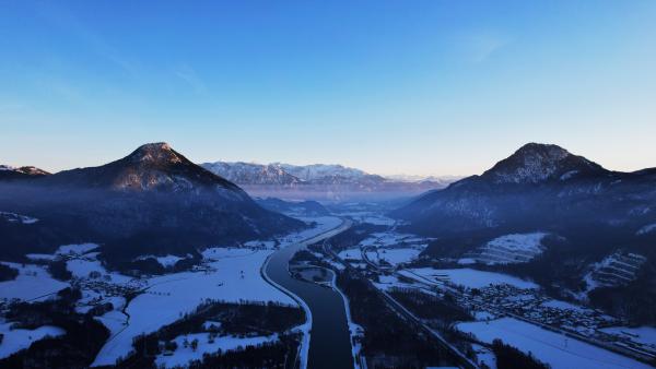 Serene landscape featuring the calm waters of the Inn river with surrounding greenery.