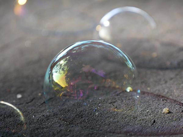 Soap bubbles on a piece of wood. Focus on a specific bubble.