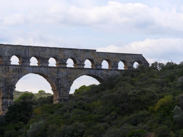 A photo of a aqueduct in France with green trees in the background.