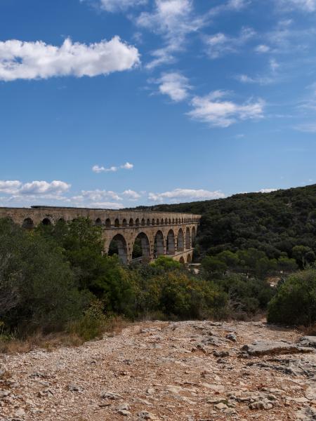 A photo of a aqueduct in France with green trees in the background.