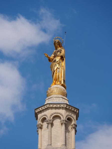 A golden statue on the top of a roof.