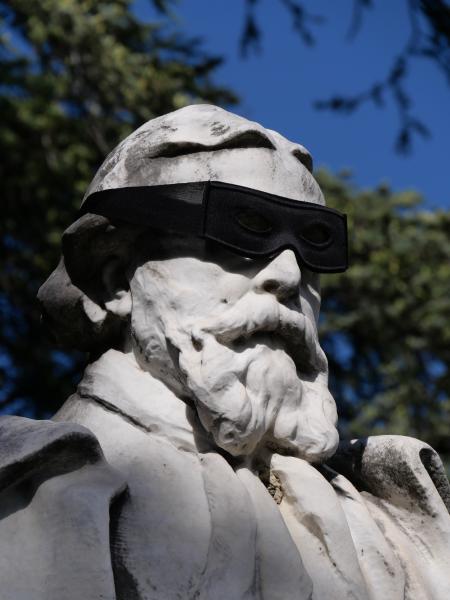 A statue on whichs head someone put a mask.