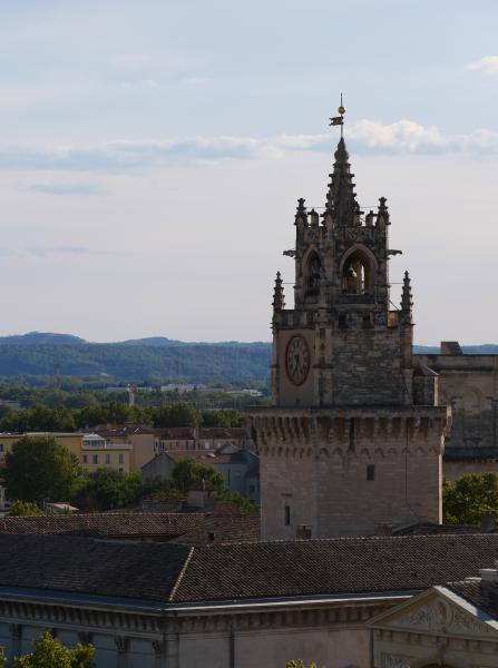 A old tower in France with a clock at it standing in a city.