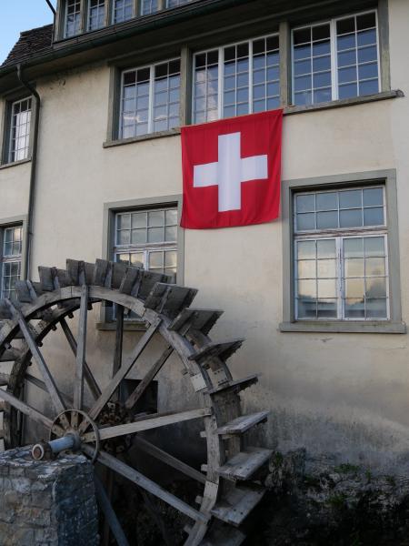 A water wheel next to a Swiss flag.