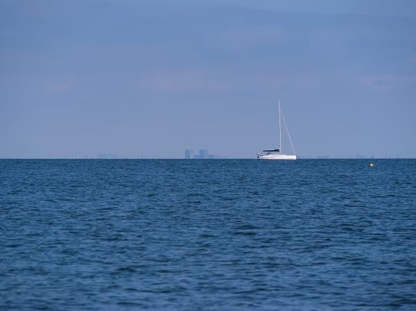 A ship swimming in the Öresund and the Copenhagen skyline in the background. The sky is slightly blue.