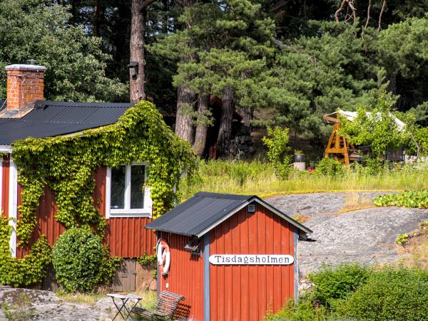 A photo of two cottages. On one there stands written Tisdagsholmen.