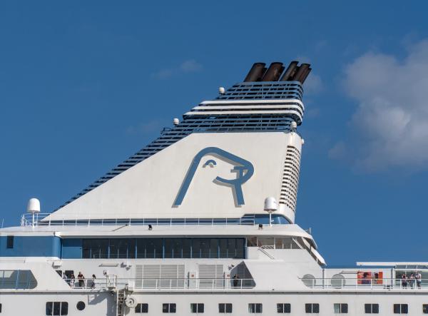 The top of a cruice ship with some clouds aboth it and a blue sky.
