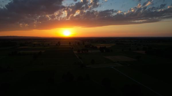 Sunset casting long shadows over the Bavarian fields, with a dramatic sky overhead.