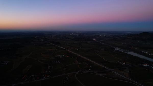 Aerial view of a Bavarian village during twilight with mountains in the backdrop and a dimly lit sky.