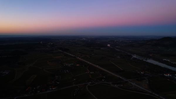 Aerial view of a Bavarian village during twilight with mountains in the backdrop and a dimly lit sky.