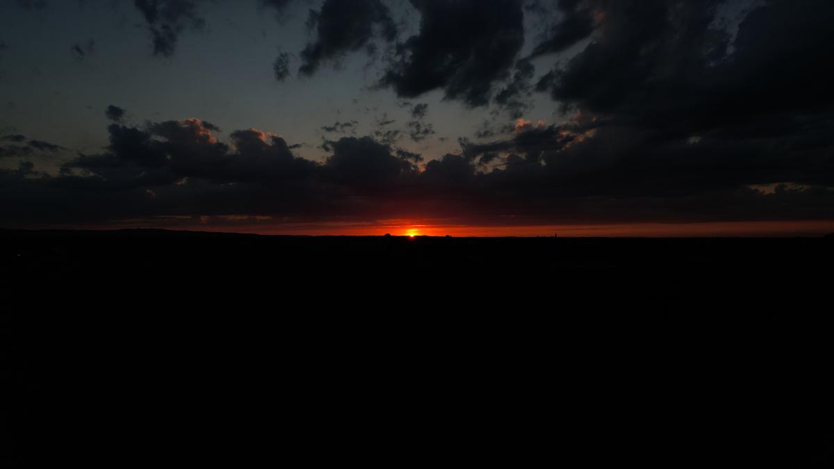 Der Sonnenuntergang erzeugt eine feurige Himmelslinie mit dunklen Wolkensilhouetten.