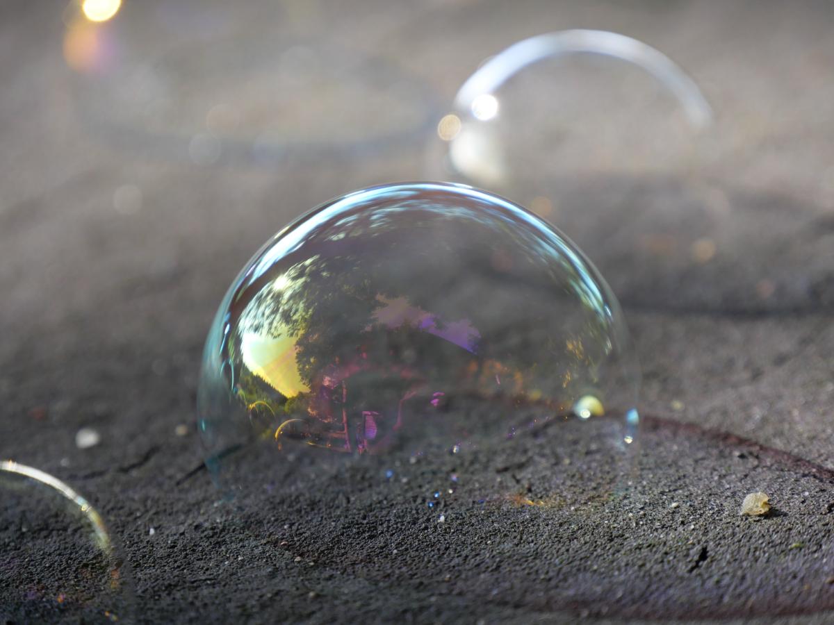 Soap bubbles on a piece of wood. Focus on a specific bubble.