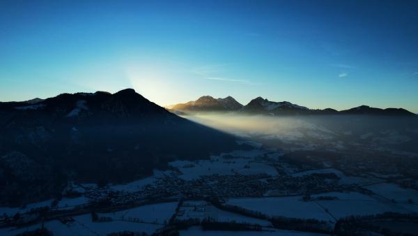 Der Sonnenaufgang erleuchtet die Gipfel der Alpen unter klarem blauem Himmel.