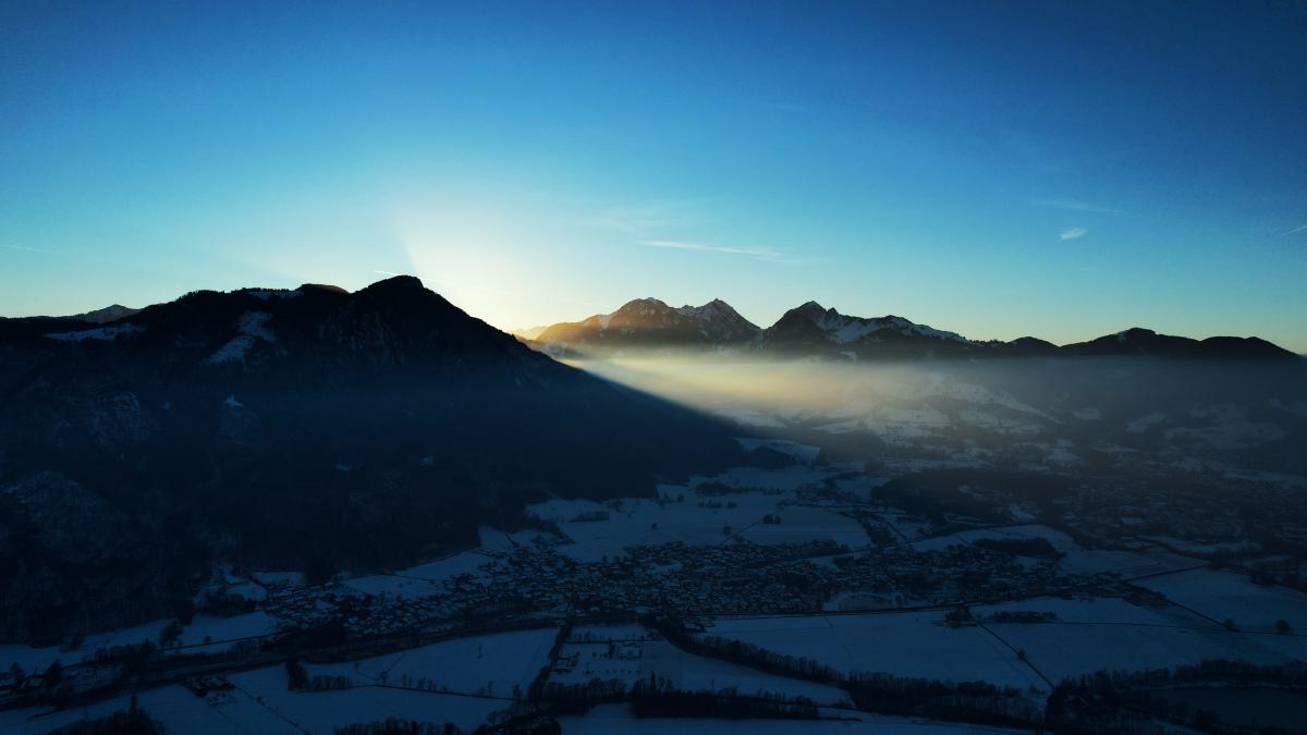 Der Sonnenaufgang erleuchtet die Gipfel der Alpen unter klarem blauem Himmel.
