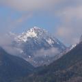 Between the Clouds - A Snowy Summit Behind the Ridges