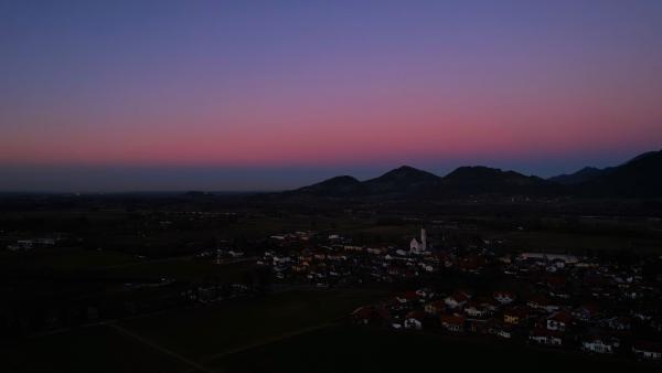 Dämmerung über einem malerischen bayerischen Dorf vor einer Bergkulisse.