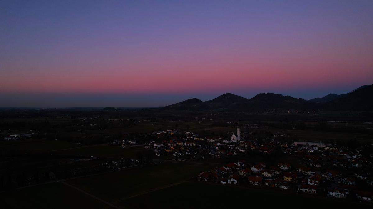 Dämmerung über einem malerischen bayerischen Dorf vor einer Bergkulisse.