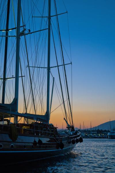 Ein Segelboot im Hafen von Bodrum in der Türkei. Im Hintergrund ist ein Sonnenuntergang zu sehen.