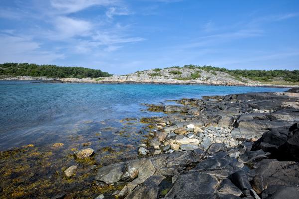 Zu sehen ist die felsige schwedische Westküste mit dem Meer und einer Landformation im Hintergrund.
