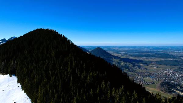 Luftaufnahme über dem Riesenkopf mit schneebedeckten Bäumen und klarem blauem Himmel.