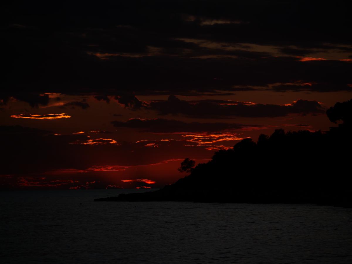 Ein dramatischer Sonnenuntergang, bei dem dunkle Wolken eine höllische Stimmung am Himmel erzeugen.
