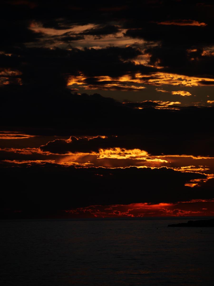 Dramatischer Sonnenuntergang mit leuchtend orangefarbenen Wolken über dem Meer.