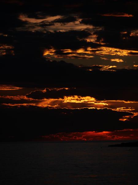 Dramatischer Sonnenuntergang mit leuchtend orangefarbenen Wolken über dem Meer.