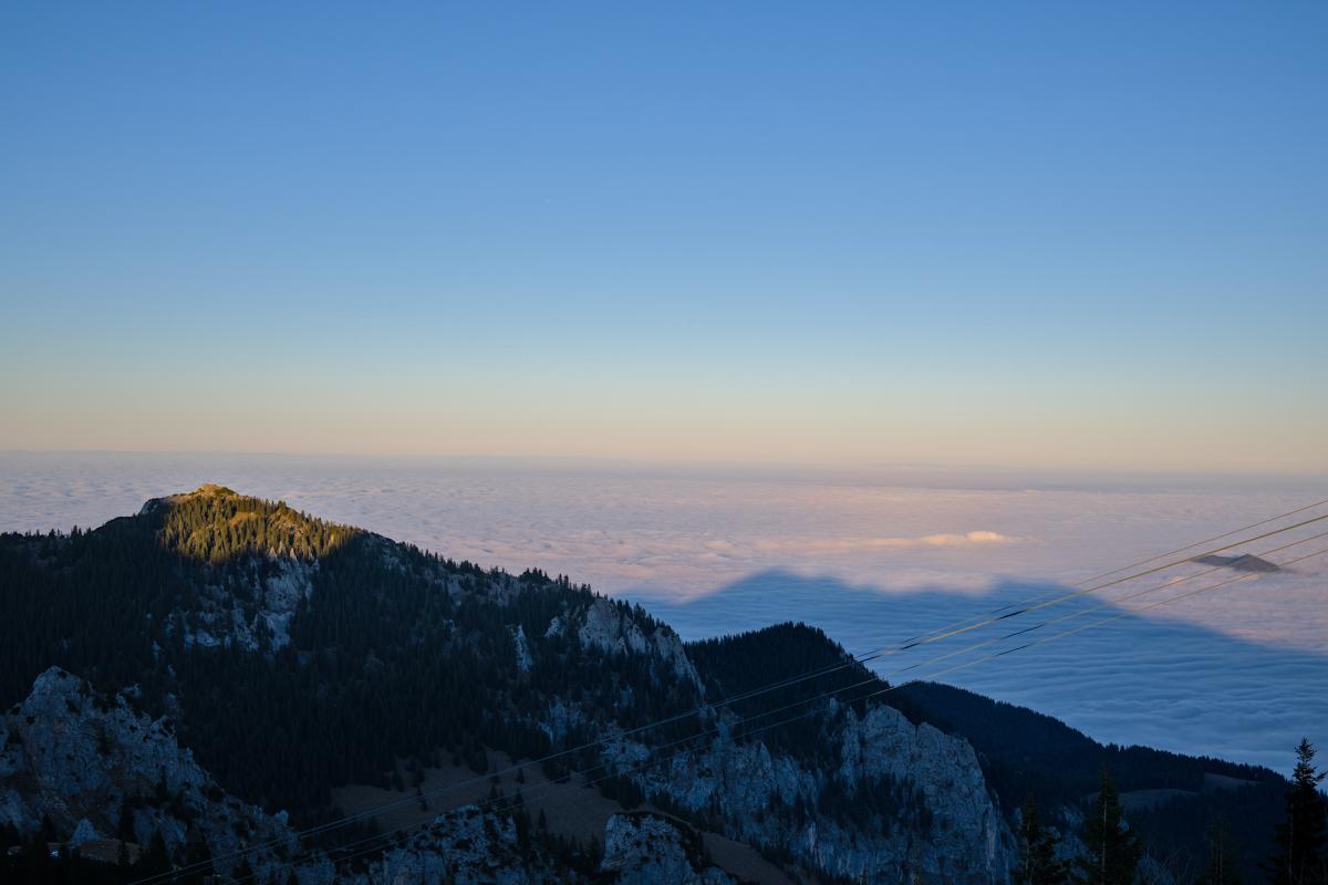 You can see a mountain in the foreground with an infinite appearing sea of clouds behind it. The sky is blue and the horizon a bit orange.