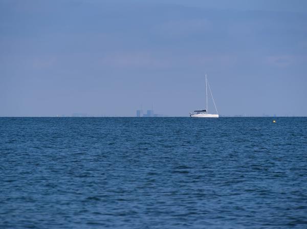 A ship sailing in the Öresund and the Copenhagen skyline in the background. The sky is slightly blue.