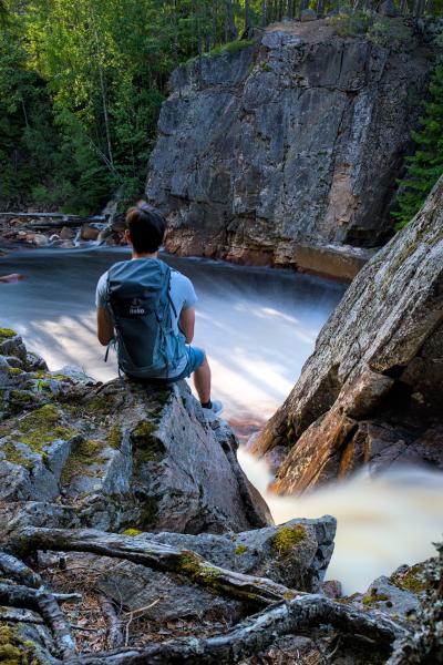 A self-portrait of me sitting on a rock next to a waterfall. The waterfall is washed out because of long exposure.