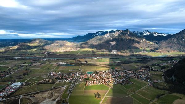 Aerial view of a village with its surrounding fields and mountains under the shadow of twilight.