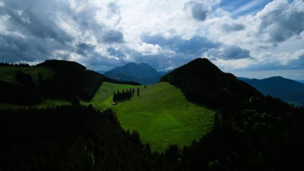 Luftaufnahme eines saftig grünen Tals mit den Bergen Rehleitenkopf und Riesenkopf im Hintergrund.
