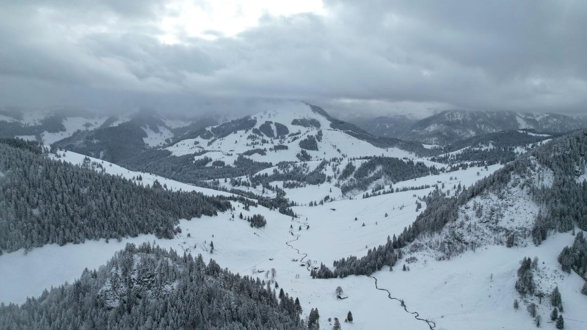 Foto eines kleinen Tals zwischen den Bergen. Das Bild entstand im Winter, und alles ist schneebedeckt.