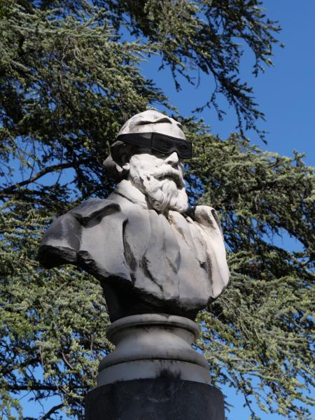 Eine Statue, auf deren Kopf jemand eine Maske gesetzt hat.