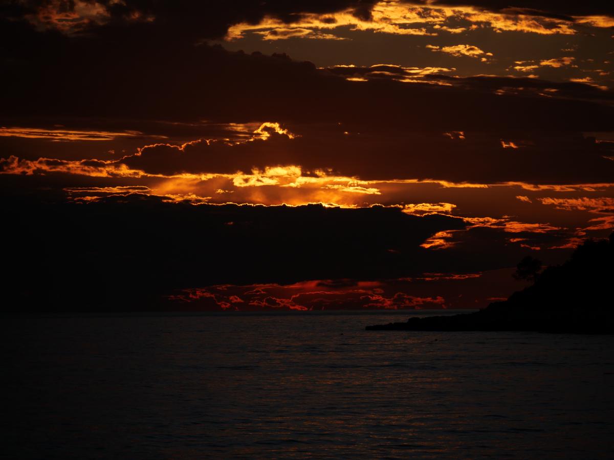 Ein glühender Sonnenuntergang mit Wolken, die in warmen Rot- und Orangetönen leuchten.