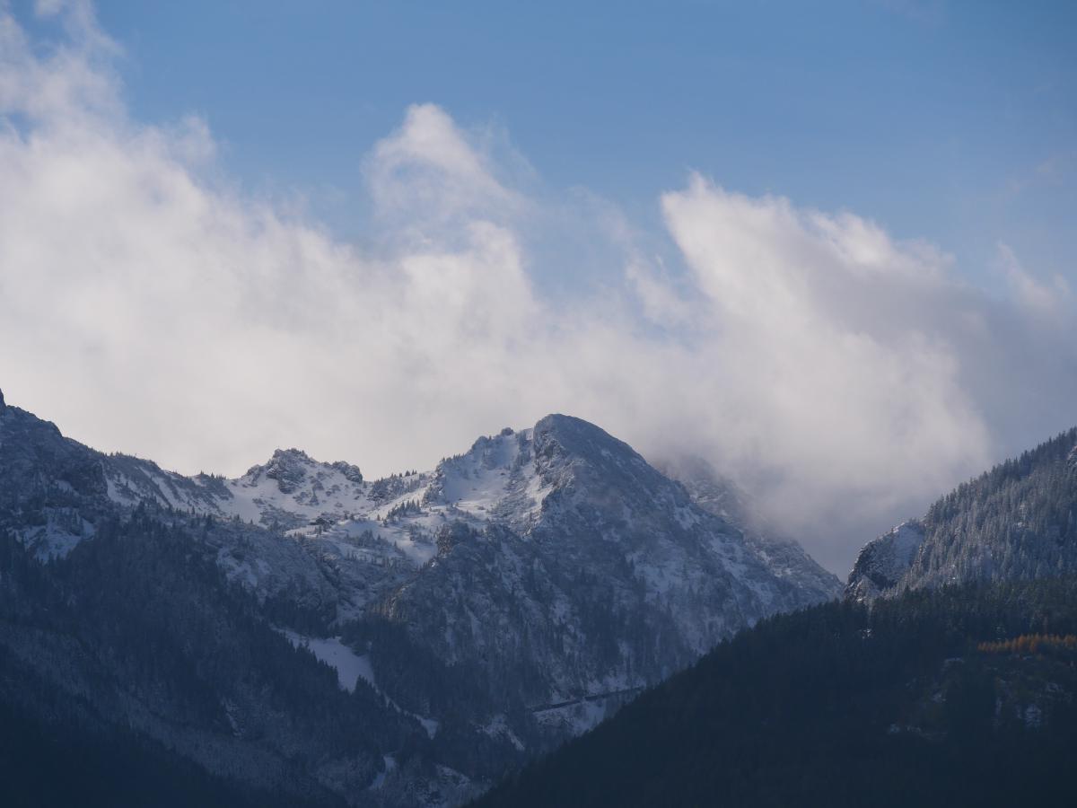Schroffes, schneebedecktes Berggelände mit Wolken, die sich um die Gipfel gelegt haben.