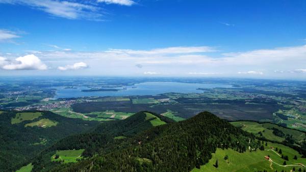Luftaufnahme des Chiemsees von den bayerischen Bergen aus, bei klarem Himmel.