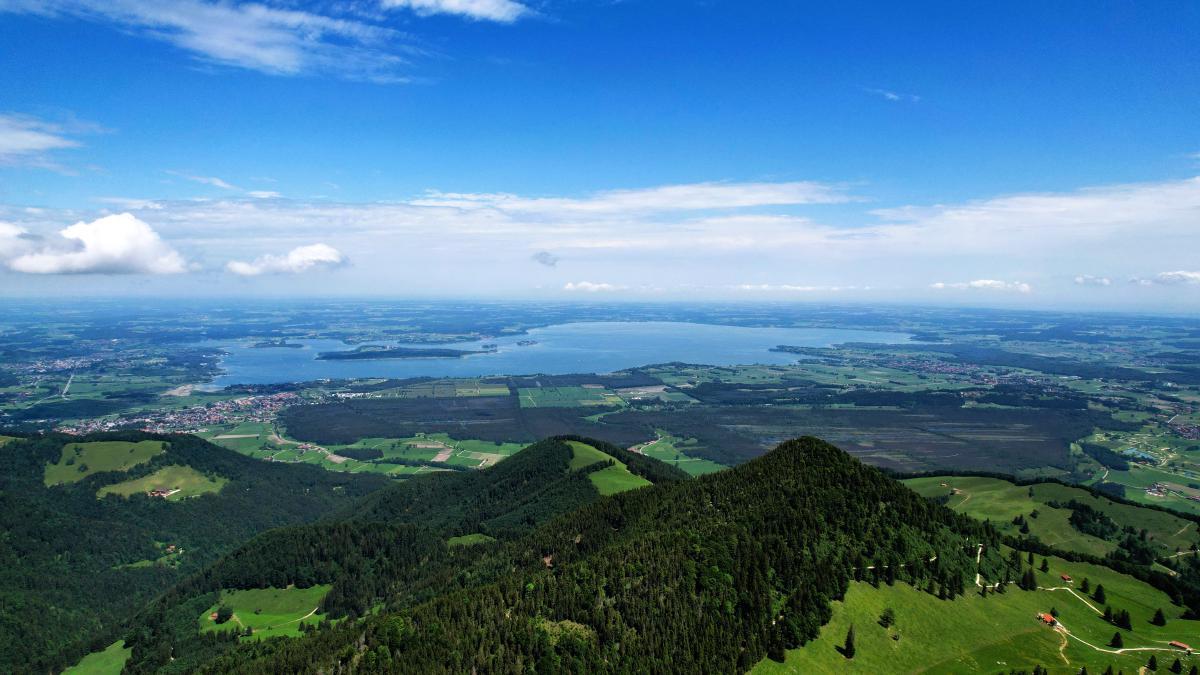 Luftaufnahme des Chiemsees von den bayerischen Bergen aus, bei klarem Himmel.